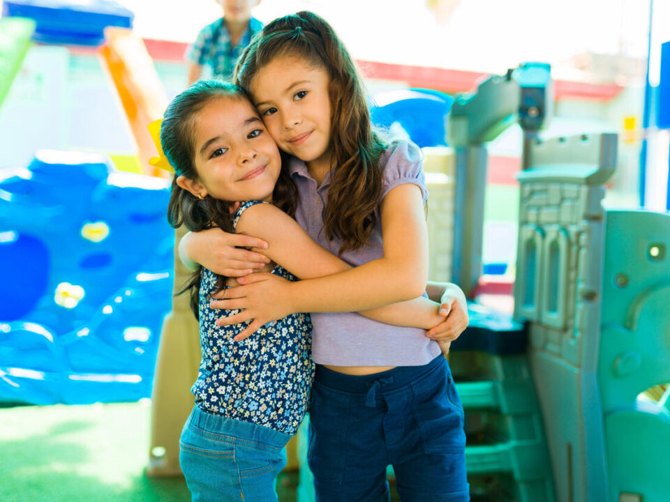 Lovely preschool friends embracing in the playground